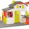 Spielhaus Neo Friends House DeLuxe Smoby Mit Sitzgelegenheit Unter Einem Sonnenschirm Im Garten Und Spielküche