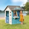 Spielhaus Mit Laden Sweety Corner Playhouse Smoby Und Eine Küche Mit Sonnenschirm Hinter Dem Zaun SM810225-e